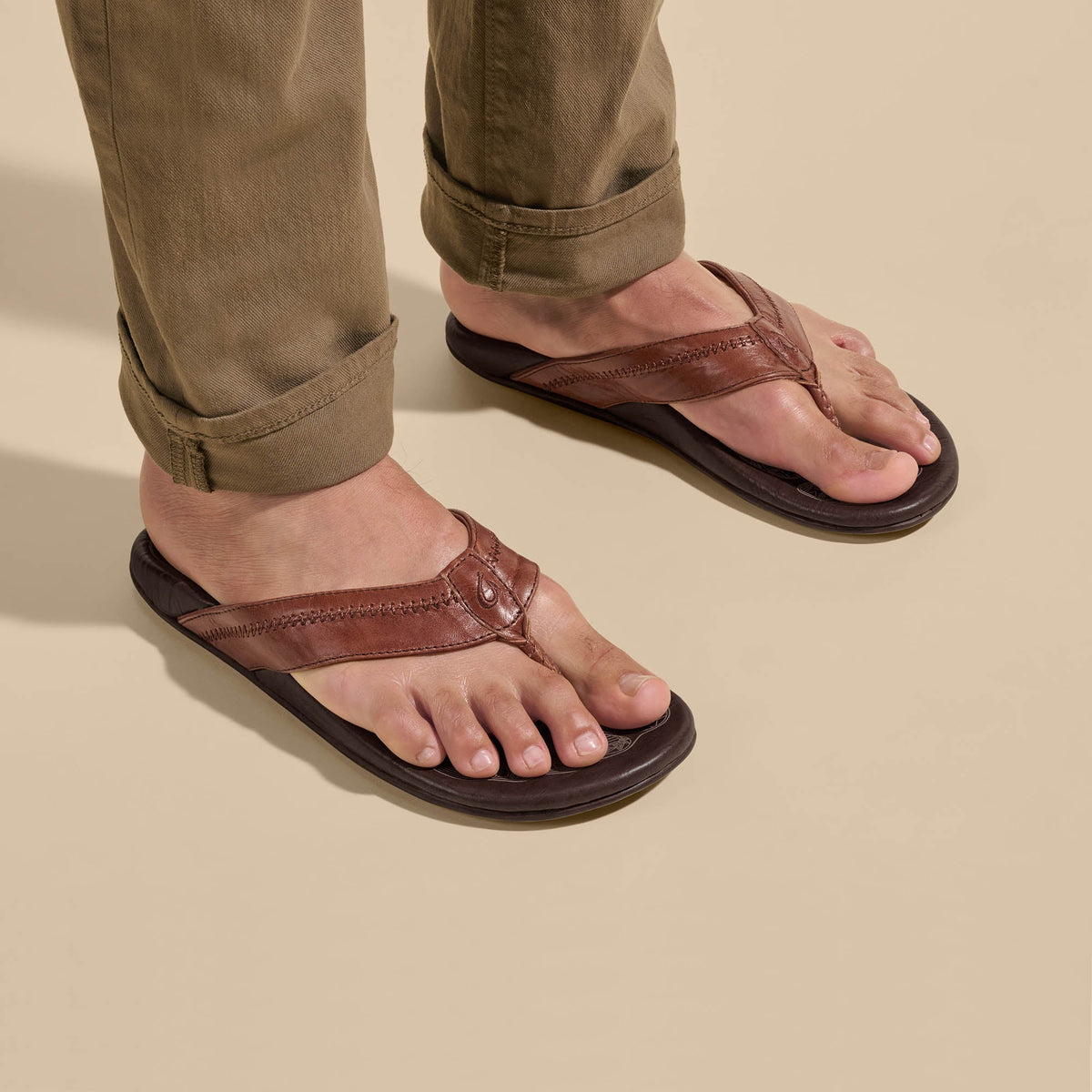 OLUKAI Men's Hiapo Rum/Dark Wood leather beach sandal, full-grain leather strap with whipstitching, detail view.