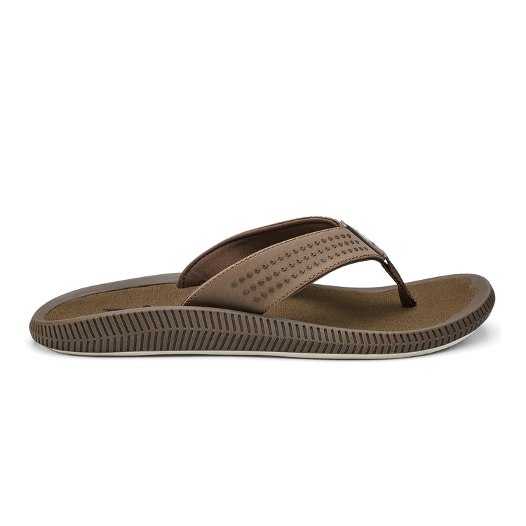 The OLUKAI Mens Ulele Brown flip-flop features a textured sole and Wide, dotted strap for foot pain relief, shown from the side against a plain white background.