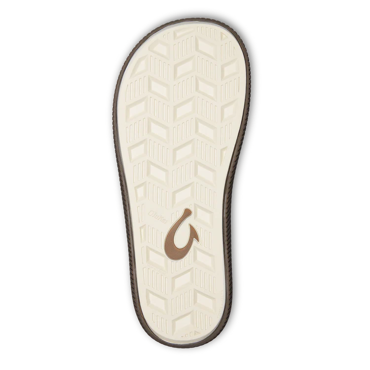 The image shows the sole of the OLUKAI Mens Ulele Brown sandal featuring a white, textured herringbone tread, a brown curved logo at the center, and a black outline.