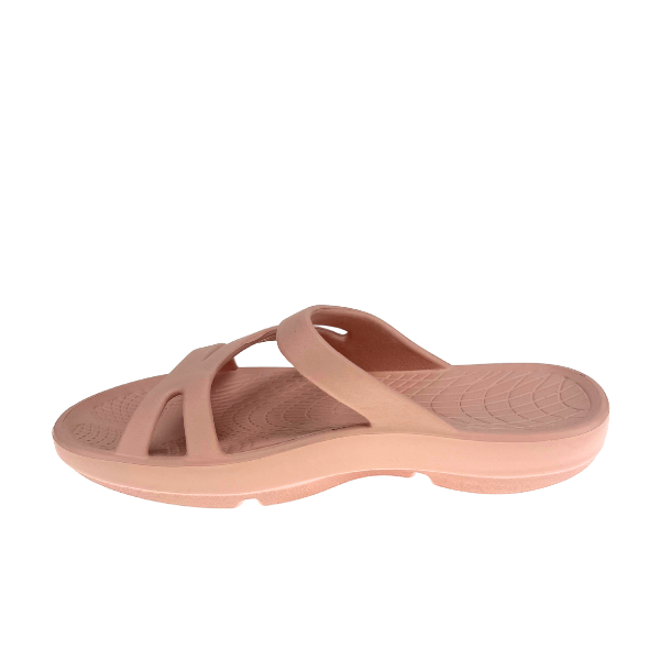 The Sovella Womens PF Slide Pink by SOVELLA is a single light pink recovery sandal with a textured footbed, open toe, and two Wide crisscross straps. It offers optimal arch support and all-day comfort, shown against a white background.