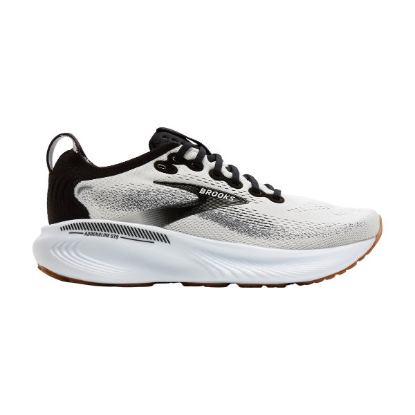 A side view of the BROOKS Women's Adrenaline GTS 25 Wide in White/Black, featuring black and gray accents, black laces, a thick cushioned sole, and a brown rubber outsole—designed for runners who need supportive comfort.
