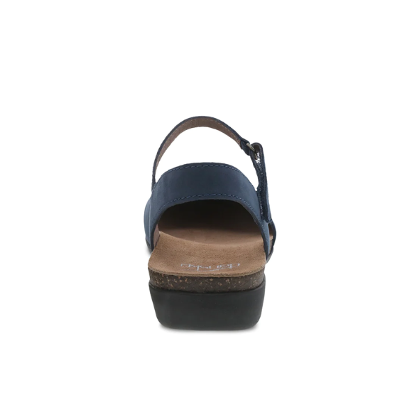 Rear view of a Dansko Womens Rowan Navy sandal by DANSKO, featuring a blue ankle strap, tan memory foam insole, and black wedge sole, photographed on a white background.