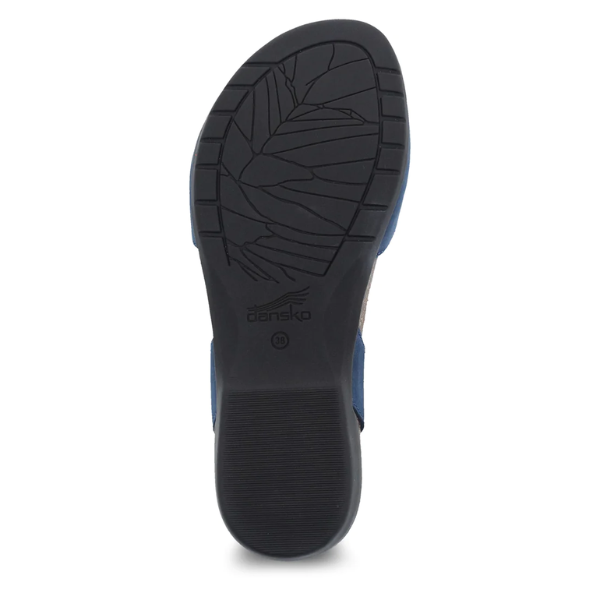 The image displays the black rubber sole of a Dansko Womens Rowan Navy shoe by DANSKO, featuring a leaf-like pattern, an embossed Dansko logo at the center, and textured horizontal lines at the heel for added support.