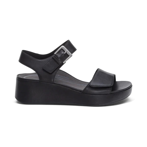 AETREX WORLDWide INCs Aetrex Womens Ariel Black sandal features an open toe, Wide front strap, adjustable silver-buckle quarter straps, and a thick wedge sole for stylish comfort and optimal foot pain support.