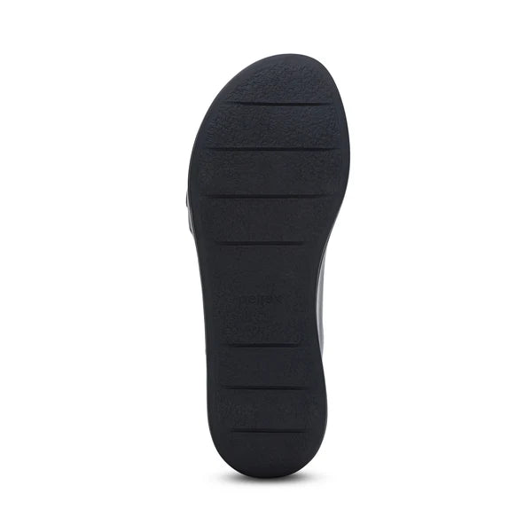 The image shows the Aetrex Womens Ariel Black shoe sole by AETREX WORLDWide INC, featuring a slightly curved shape and horizontal grooves for traction, designed to support foot pain. The textured sole is displayed against a white background.