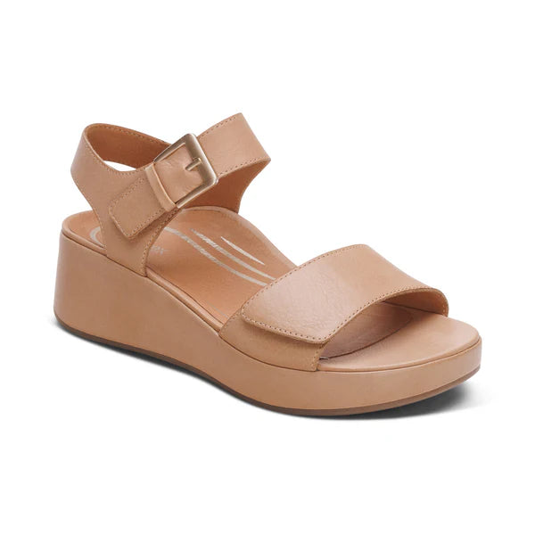 The Aetrex Womens Ariel Sand by AETREX WORLDWide INC is a beige platform sandal with an open toe, Wide front strap, and adjustable buckle quarter straps on a low wedge heel—enjoy foot pain relief in this simple, modern style.