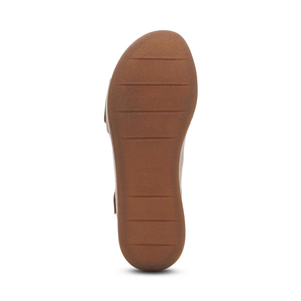 The image shows the bottom view of the Aetrex Women's Ariel Sand by AETREX WORLDWide INC, featuring a brown sole with a textured grip and four horizontal grooves for traction, rounded shape, and simple design typical of wedge sandals.