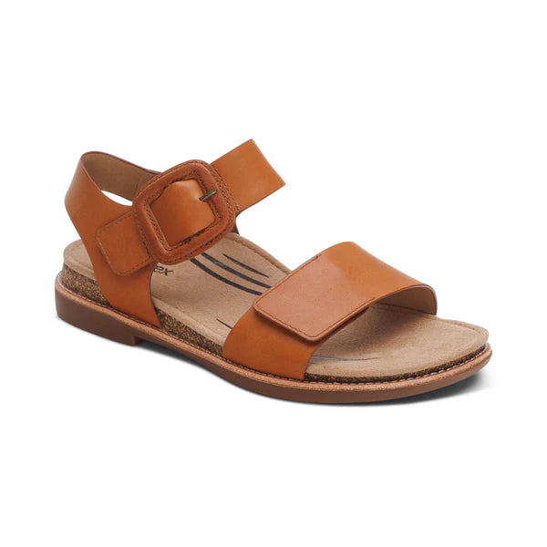 The Aetrex Womens Claire Cognac by AETREX WORLDWide INC is a brown leather sandal with a Wide toe strap, large buckle-adjustable straps, and a flat sole with a low heel for comfort.