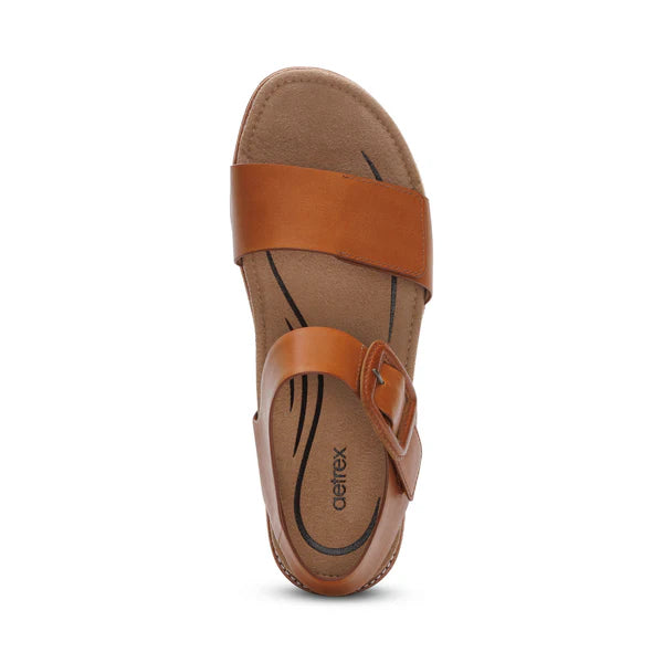 Top view of the Aetrex Womens Claire Cognac sandal by AETREX WORLDWide INC, featuring a tan Wide front strap, adjustable ankle strap with side buckle, and a cushioned footbed with arch support and decorative lines.