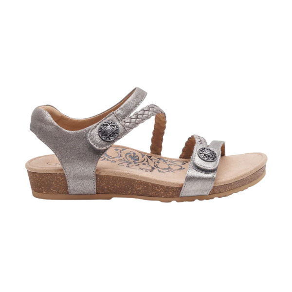 The Aetrex Womens Jillian Brushed-Silver sandal by AETREX offers a low cork wedge heel, two adjustable straps with decorative buttons, a braided upper design, and features an orthotic floral-patterned footbed for comfort.