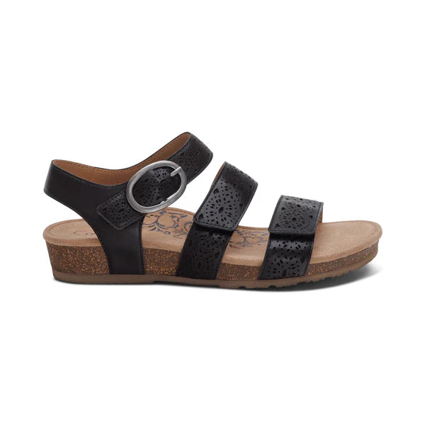 Aetrex Womens Lilly Cutout Black by AETREX features three adjustable straps with perforated detail, a decorative buckle, open toe and heel, a tan cork wedge sole, and a memory foam footbed for comfort and arch support.