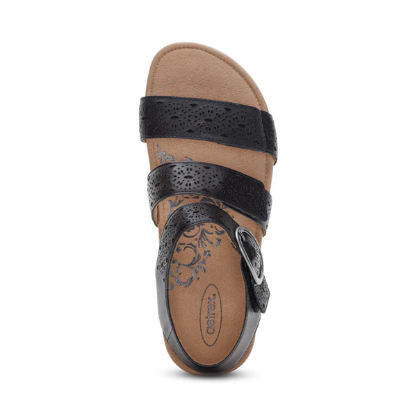 A top view of the Aetrex Womens Lilly Cutout Black sandal by AETREX WORLDWide INC, featuring three black straps (one with a side buckle), arch support, and a tan footbed with a floral pattern near the heel.