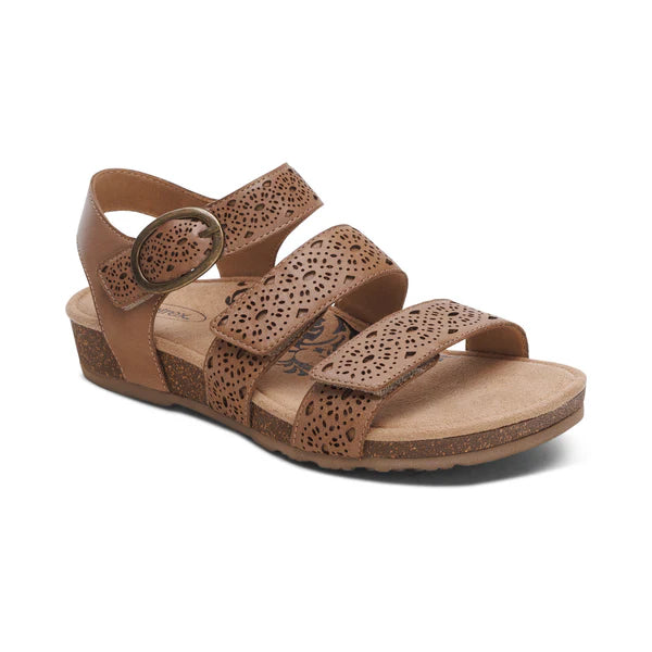 The Aetrex Womens Lilly Cutout Taupe by AETREX WORLDWide INC is a taupe leather sandal with three adjustable straps, cutout designs, round buckle, memory foam footbed, cushioned sole, arch support, low wedge heel, and open toe.