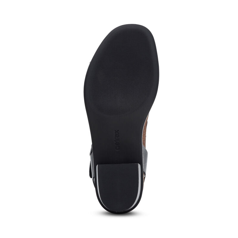 The image displays the bottom view of the Aetrex Women's Mae Black sandal by AETREX WORLDWide INC, featuring a textured sole, block heel, and "aetrex" embossed on the sole, all set against a white background.