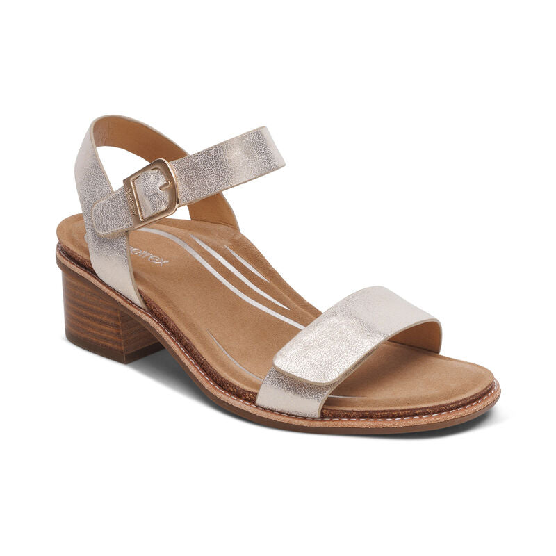The Aetrex Womens Mae Champagne sandal by AETREX WORLDWide INC features metallic beige leather straps, an open toe, low wooden block heel, cushioned tan insole for comfort, and an adjustable quarter strap with buckle.