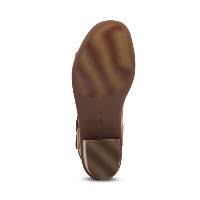A bottom view of the Aetrex Womens Mae Cognac shoe by AETREX WORLDWide INC shows its textured rubber sole, low block heel, and Aetrex branding near the heel.