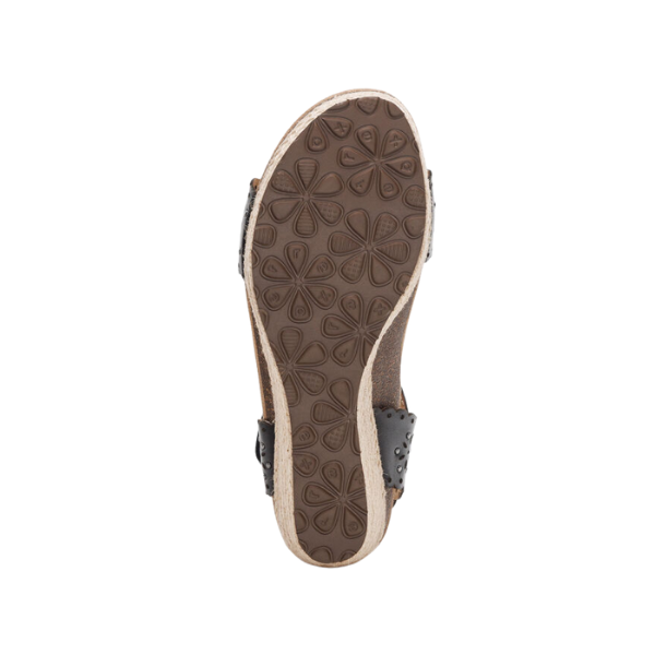 The image shows the bottom of the Aetrex Womens Sydney Black Cutout sandal by AETREX WORLDWide INC, featuring a textured sole with a floral pattern, cork-like edge, and black straps accented with visible metal studs.