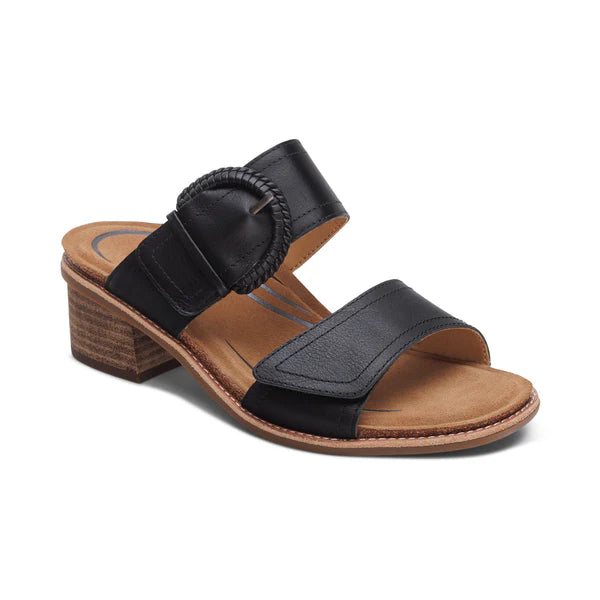 The Aetrex Women's Tatiana Black by AETREX WORLDWide INC features two wide leather straps, a round buckle, open-toe design, tan footbed, and a low stacked heel—delivering stylish comfort and foot pain relief all day.