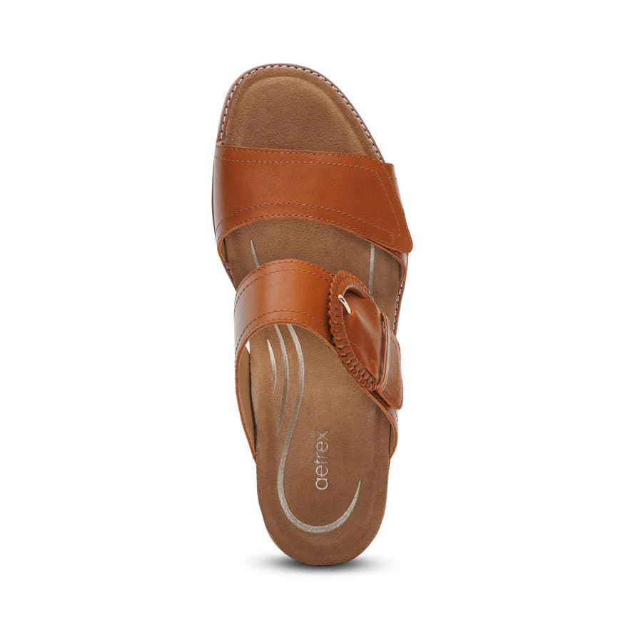 Top view of a single Aetrex Womens Tatiana Cognac slip-on sandal by AETREX WORLDWide INC, featuring brown leather, visible stitching, a cushioned insole for foot pain relief, and the Aetrex brand printed on the footbed.