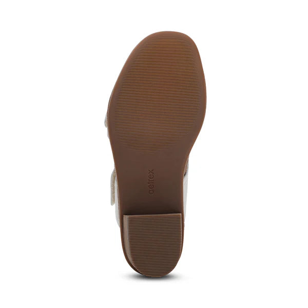 The image shows the bottom view of an ivory Aetrex Womens Tatiana shoe by AETREX WORLDWide INC with a textured rubber sole, low block heel, and aetrex embossed near the arch, designed for foot pain relief.