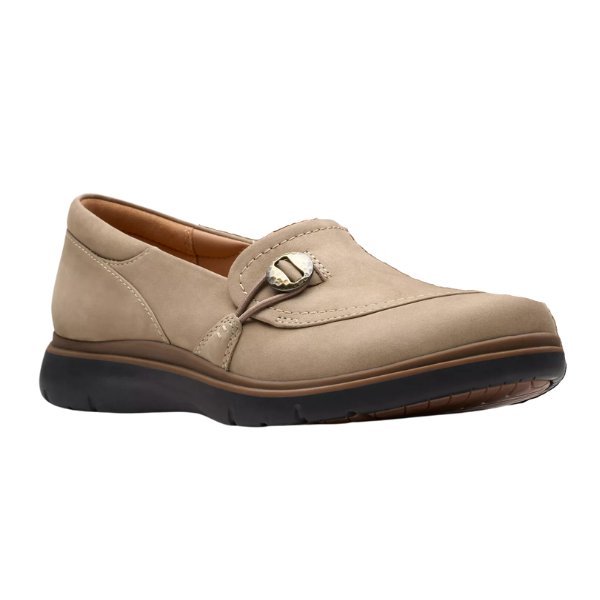 The CLARKS Certina Ease Wide Pebble is a beige slip-on loafer made from pebble nubuck, with a decorative buckle, cushioned sole, removable footbed, and a black textured rubber outsole.