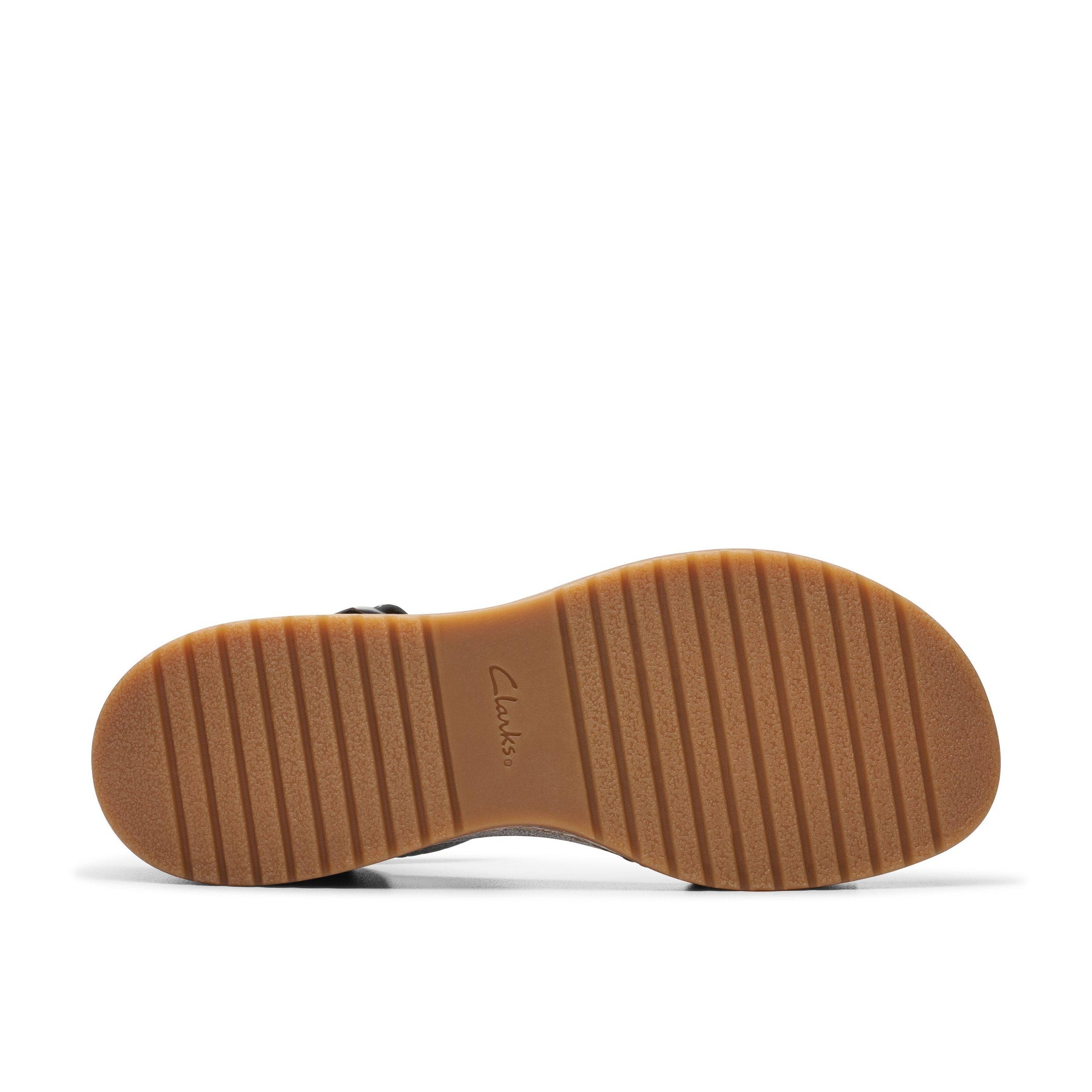 The image shows the sole of the Clarks Womens Kassandra Lily Black sandal, with a light brown, ridged rubber surface engraved with CLARKS, plus a cork-effect wedge heel and horizontal grooves for stylish traction.
