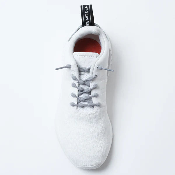 A white athletic slip-on shoe viewed from above features CATERPY RUN NO-TIE LACES GREY by CATERPY, gray elastic laces, a black heel tab with white text, a red inside lining, and is set against a plain white background.