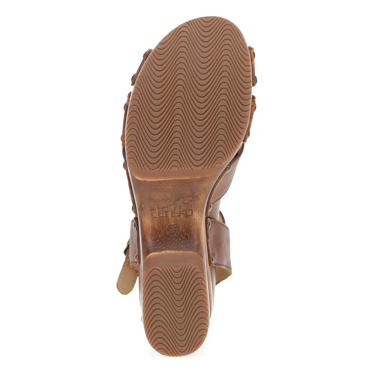 The image displays the sole of the Dansko Womens Alanna Tan sandal by DANSKO, featuring a brown base with a wavy tread pattern and embossed branding and logo at the center, designed for foot pain relief.