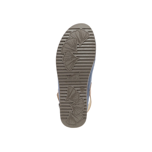The image shows the sole of the DANSKO Womens Merrin Blue mule, featuring a textured pattern with two ginkgo leaf designs and horizontal grooves. The light brown sole is photographed from below against a white background.
