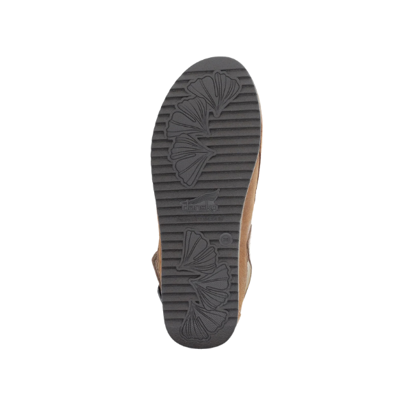 The image shows the bottom view of the DANSKO Womens Merrin Tan mule with a black rubber sole featuring ridged and leaf-shaped treads for superior grip and foot pain relief, set against a white background.