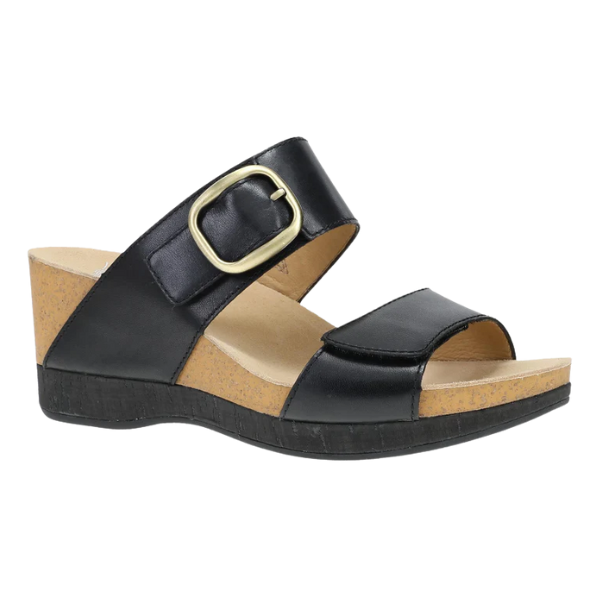 The Dansko Womens Shannon Black Burnished by DANSKO is a black wedge slide sandal with two Wide leather straps, a large gold buckle, an open toe, and a cork-textured sole for foot pain relief with a low heel.