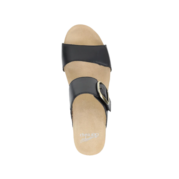 A single Dansko Womens Shannon Black Burnished wedge slide sandal by DANSKO, featuring two straps (one with a large buckle) and a tan cushioned footbed for pain relief, shown from above.