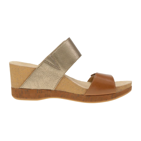 The DANSKO Dansko Womens Shannon Gold/Tan is a wedge slide sandal with a cork sole, metallic gold upper strap, and brown lower strap—ideal for foot pain relief and stylish comfort, inspired by the classic design.