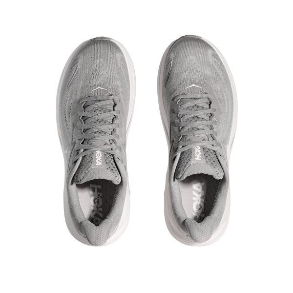 A pair of HOKA Mens Clifton 10 Wide Grey running shoes with white outsoles, designed for foot pain relief. Viewed from above on a white background, they feature laces and visible HOKA branding on the tongue and insole.