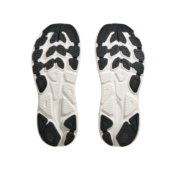 Overhead view of two white and black athletic shoe soles with textured treads, side by side on a white background, highlighting the plush cushioning and performance of the HOKA Mens Clifton 10 Wide Navy running shoes.