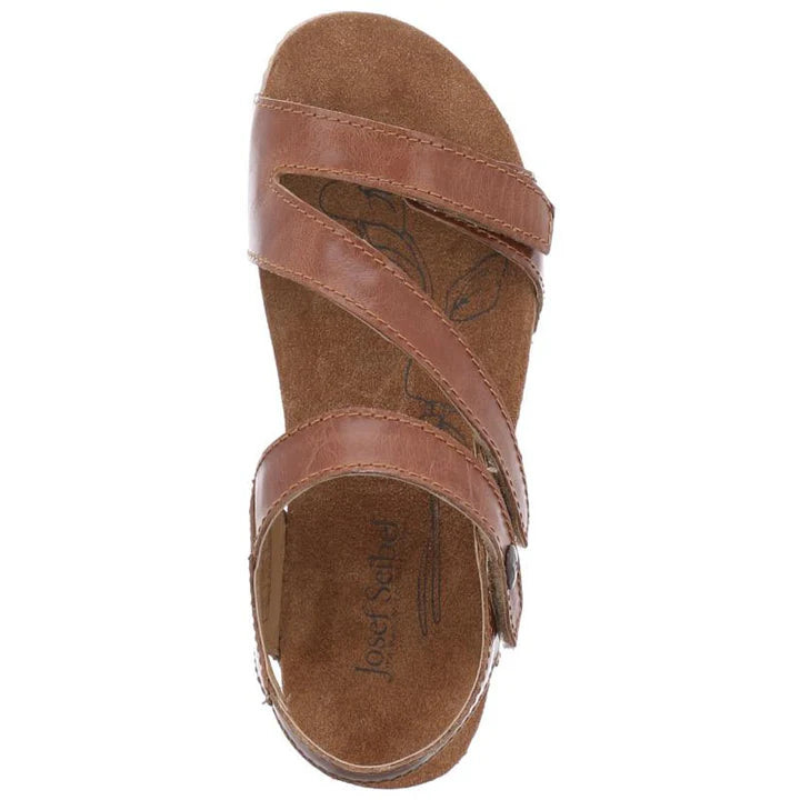 The Josef Seibel Womens Tonga Camel sandal features two diagonal adjustable straps and one horizontal strap in brown, with an open toe, suede-like floral-patterned insole, and Josef Seibel branding.