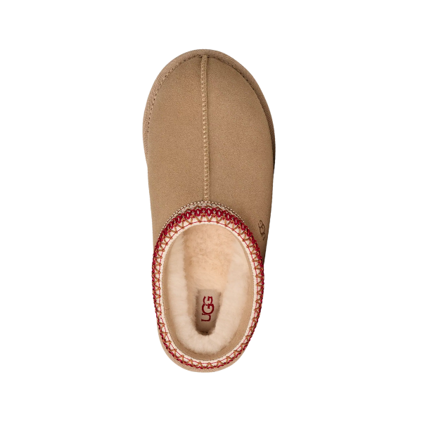 Top view of the UGG Women's Tasman II Sand slide by UGG, featuring a fuzzy cream interior and red patterned trim. This sheepskin slipper displays the signature UGG logo on its insole for a classic finish.