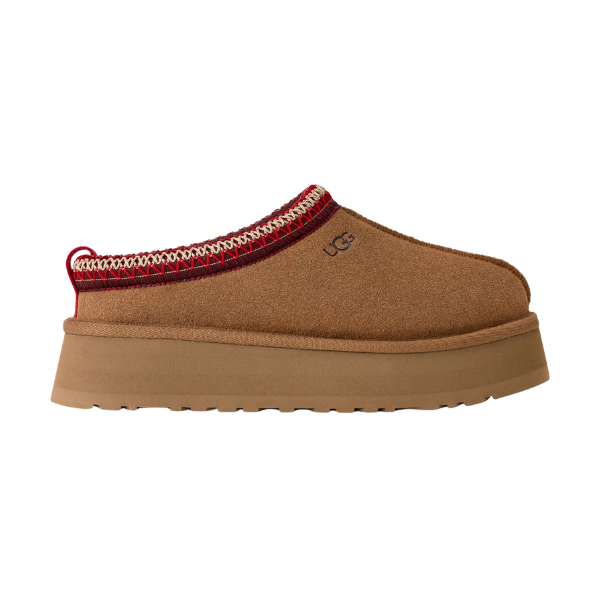The UGG Women's Tazz II Chestnut is a stylish suede platform slipper with a thick tan sole, cozy sheepskin lining, red and white trim, and the signature UGG logo—ideal for comfort and style.