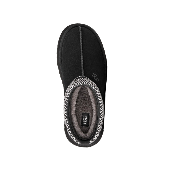 The UGG Women's Tazz II Black slipper features soft gray sheepskin lining and decorative stitching, shown from above against a white background.