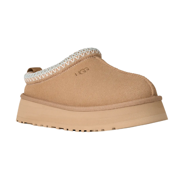 UGG Women's Tazz II Sand: Tan slip-on platform sandal with thick sole, white stitching, UGG logo on the side, closed toe, backless heel, and cozy sheepskin lining for comfort.