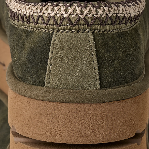 Close-up of the heel of UGG Men's Tasman Baxter Burnt Olive in green suede, with cream and brown criss-cross stitching and a thick brown rubber sole—highlights the signature style of UGG.