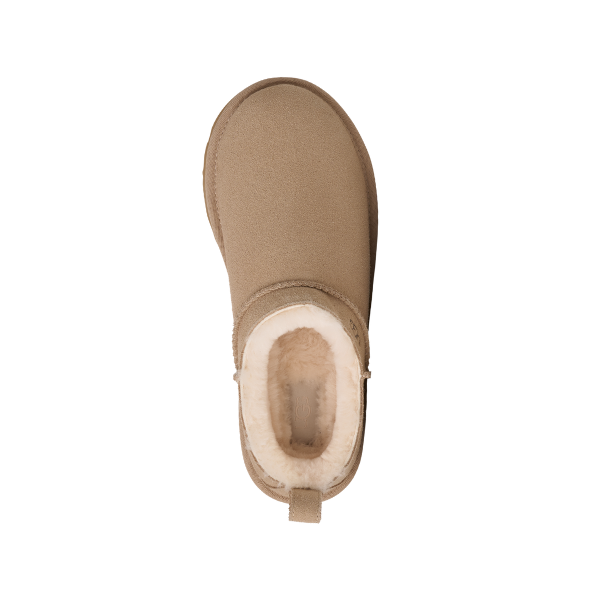 The UGG Women's Classic Micro Sand suede ankle boot, viewed from above, has a rounded toe, soft white fluffy lining, back pull tab, and a slightly textured sole. The background is white.
