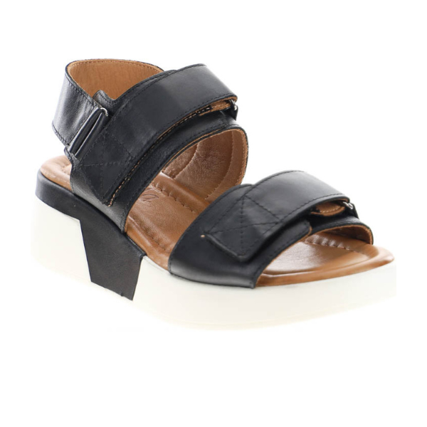 The Sovella Womens Maya Black sandal by SOVELLA offers velcro straps, a tan cushioned insole for comfort, and a thick white platform sole.
