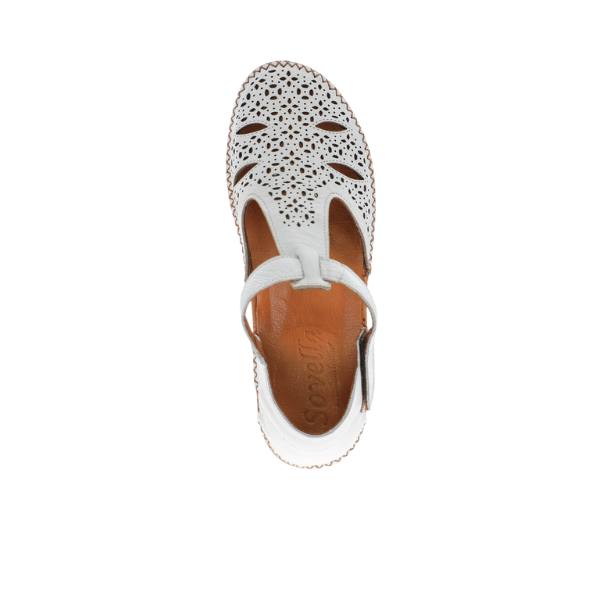 Top view of the Sovella Womens Sabrina White sandal by SOVELLA, featuring white leather with decorative cut-outs, a closed toe, T-strap design, cushioned insole for comfort, and tan insole displaying the SOVELLA brand name.