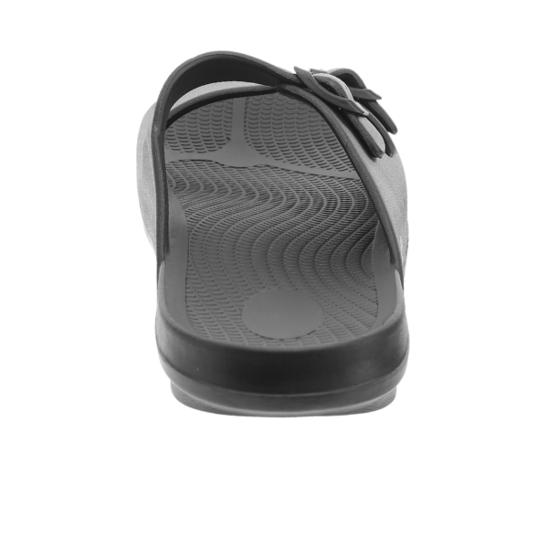 The Sovella Womens Buckle Slide Black by SOVELLA features a black and gray design, textured footbed with arch support, single toe post, and a side buckle on the strap, shown from the front against a white background.