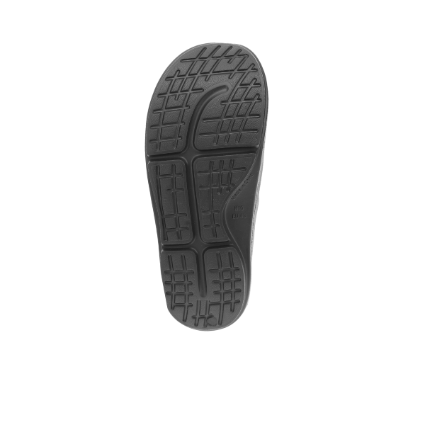 The image shows the bottom view of the Sovella Womens Buckle Slide Black by SOVELLA, featuring a textured black rubber sole with non-slip horizontal and vertical grooves for reliable grip and arch support.