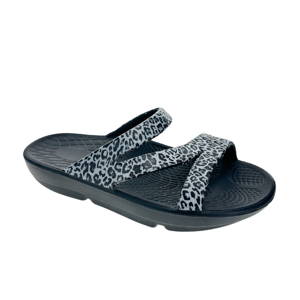 The SOVELLA Womens PF Slide Black/Leopard sandal features two crisscrossing gray and black leopard print straps, designed for comfort recovery and arch support, shown against a plain white background.