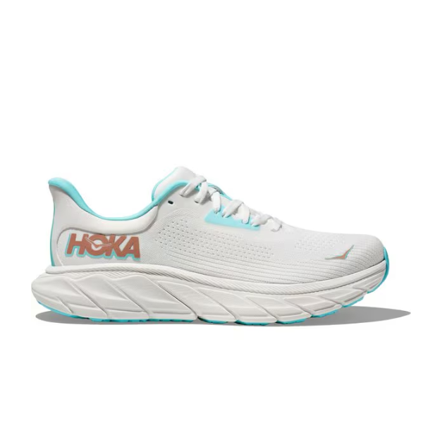 The HOKA Womens Arahi 7 (Medium Width) in White/Gold is a stability shoe with gold accents, the HOKA logo on the side, a thick cushioned sole, and J-Frame™ technology for support, shown against a plain white background.