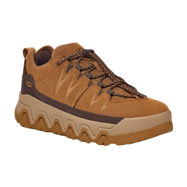 The UGG Mens Captrail Low Chestnut sneaker features waterproof suede in tan, brown laces, a brown and tan zigzag Spider Rubber sole, and side UGG branding, shown from a front-side angle.