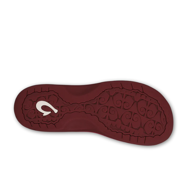 The OLUKAI Womens Ohana Red Earth/Bordeaux features a maroon sole with textured swirls, an anatomical footbed for comfort, and a white curved logo near the heel.